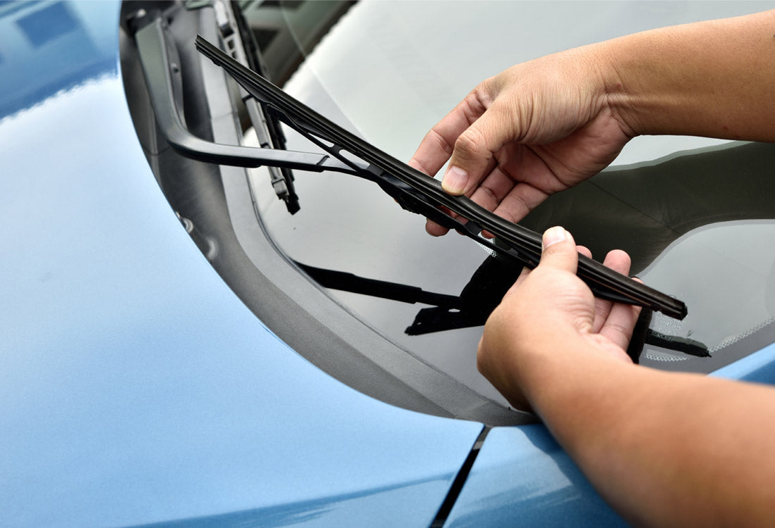 Hand installing a wiper blade on a car